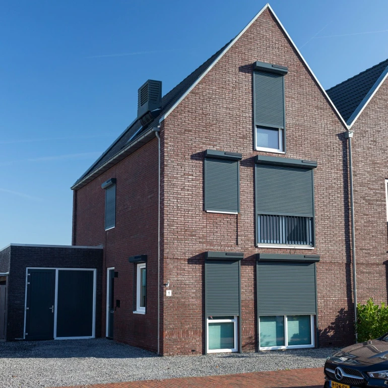 Solar rolluiken op zonne-energie op een woning met rode baksteen